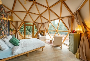 Un coin nuit confortable aménagé dans l'un des dômes géodésiques en Suisse, avec vue sur le paysage grâce à une toile transparente