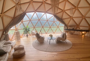 Aménagement du coin salon dans l'un des dômes géodésiques en Suisse avec vue sur le paysage grâce à une toile transparente