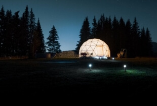 Vue de l'extérieur d'un dôme géodésique éclairé en pleine nuit