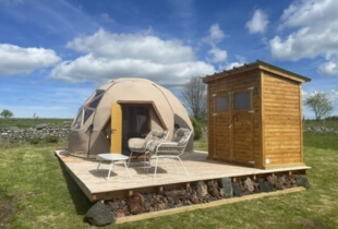 Vue de l'extérieur d'un dôme géodésique de 4m, installé sur une petite terrasse en bois