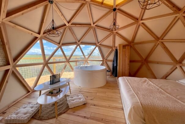 Vue de l'intérieur d'une chambre d'un dôme géodésique de 5m avec une partie de la toile transparente qui permet de voir le paysage