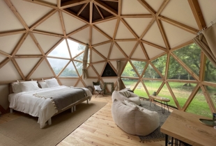Vue de l'intérieur d'une chambre d'un dôme géodésique de 6m avec une partie de la toile transparente qui permet de voir les arbres à l'extérieur