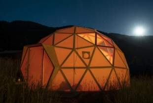 Vue de l'extérieur d'un dôme géodésique éclairé en pleine nuit