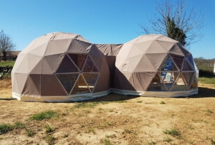 Photo montrant deux dômes géodésiques connectés installé sur de l'herbe