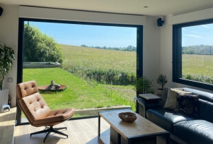 Coin salon d'un studio modulaire en suisse, avec une grande baie vitrée pour une vue sur l'extérieur