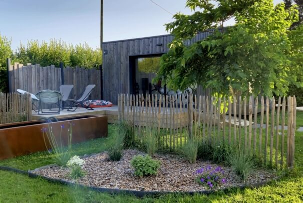 Studio de jardin et sa terrasse avec chaises longues et parterre de plante au premier plan