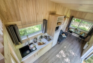 Vue depuis l'étage de la tiny house l'intrépide sur la cuisine équipée ainsi que le salon